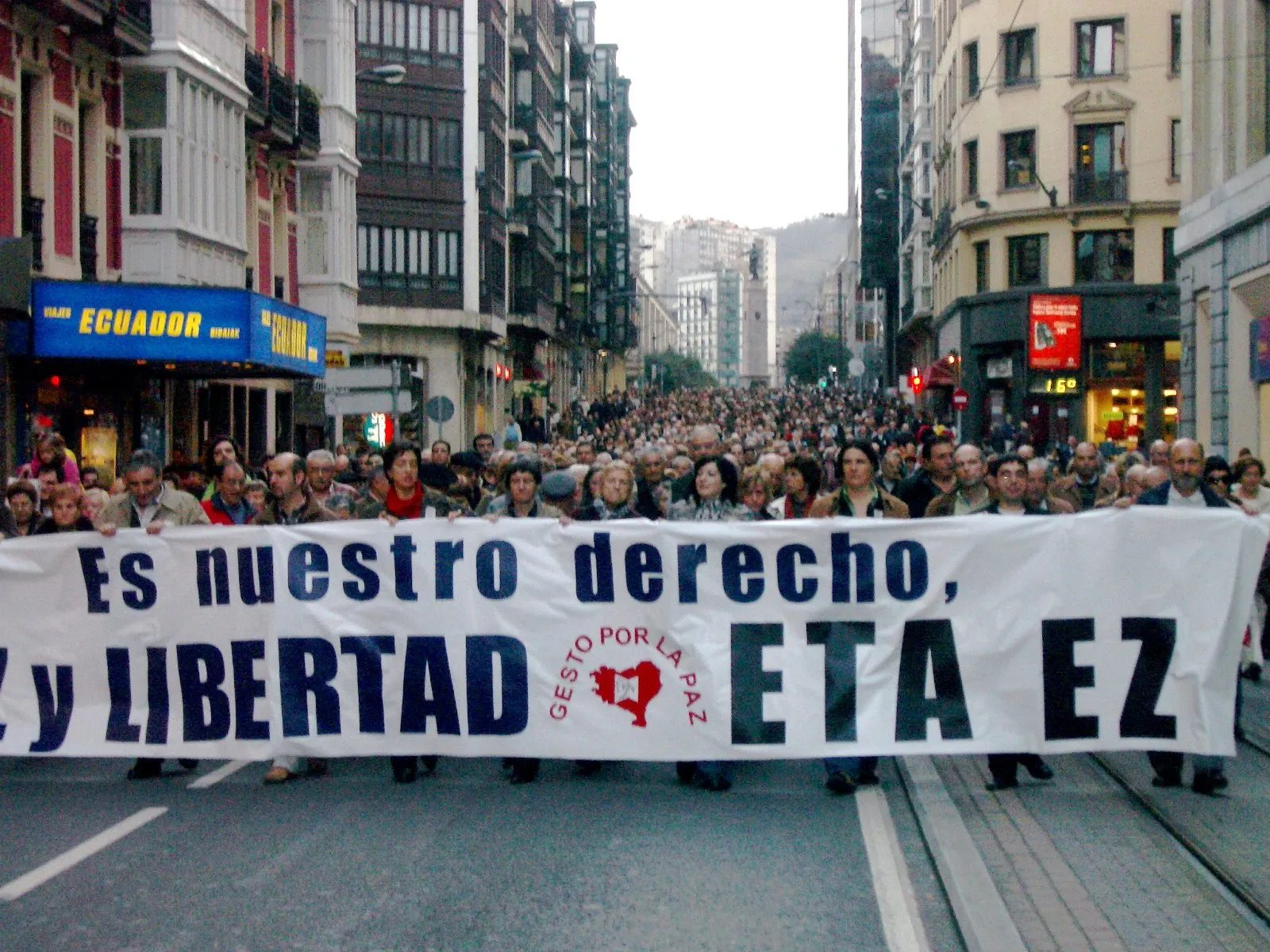 Cabecera de una manifestación en una calle de Bilbao con una gran pancarta blanca que termina con las palabras «ETA EZ» y el logotipo de Gesto por la Paz