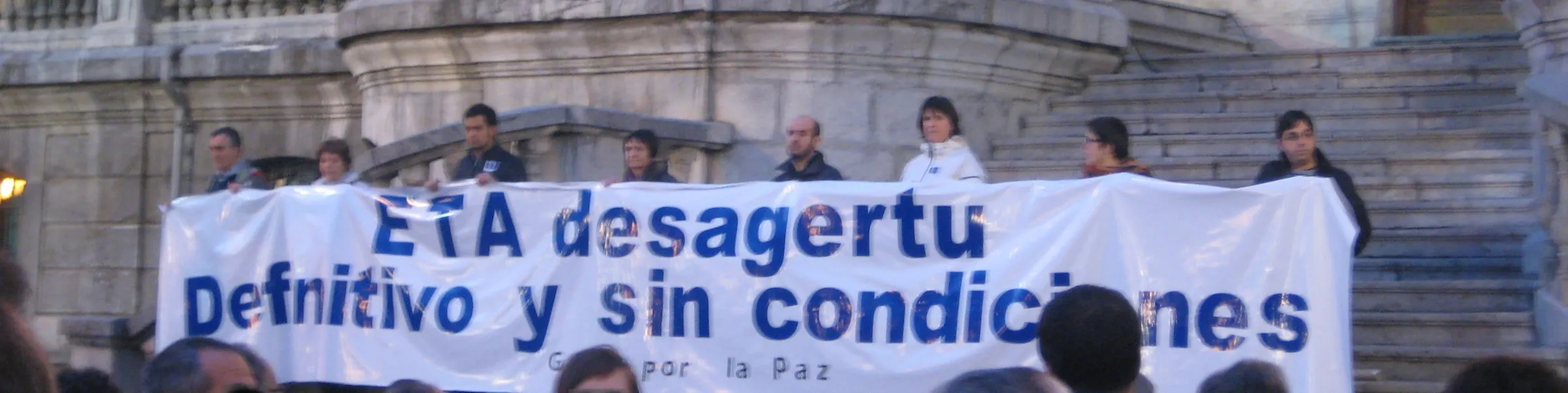 Una pancarta blanca de Gesto por la Paz en las escaleras del Ayuntamiento de Bilbao con el texto «ETA desagertu. Definitivo y sin condiciones»