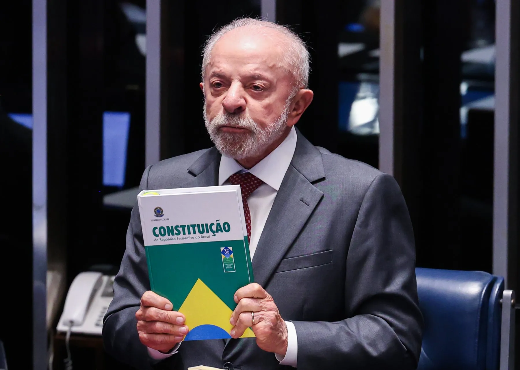 Luiz Inácio Lula da Silva, con traje gris, sostiene un ejemplar de la Constitución de Brasil en el pleno del Senado
