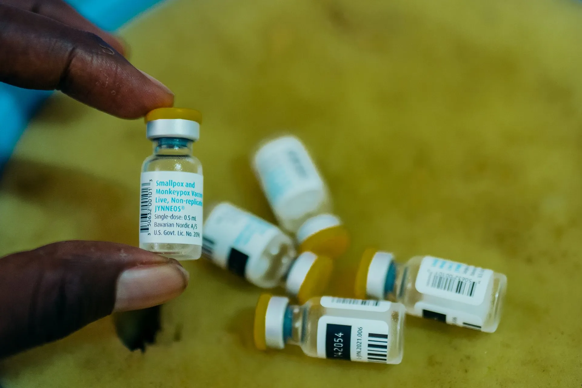 Varios viales de la vacuna contra la mpox sobre una mesa, uno de ellos sostenido entre los dedos