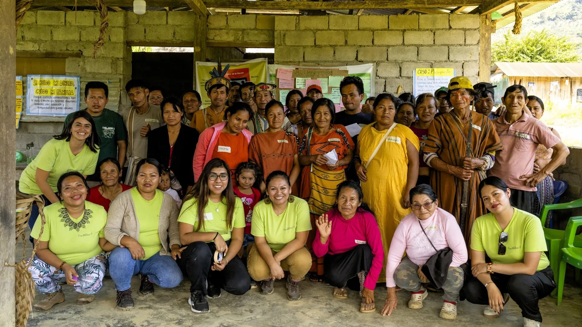 Un grupo numeroso de vecinos de la comunidad, algunos con cushmas tradicionales, posa con el equipo del programa, vestido con camisetas verdes