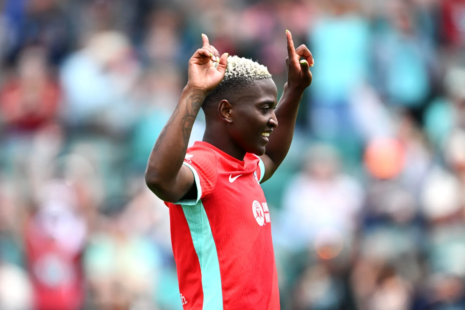 Temwa Chawinga, con la camiseta roja del Kansas City Current, sonríe y señala al cielo con los dos índices en un estadio lleno
