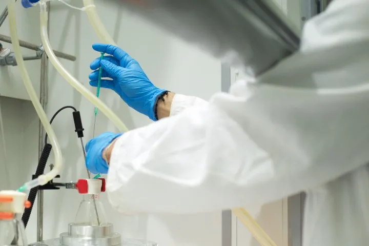 Una investigadora con guantes azules trabaja con material de laboratorio