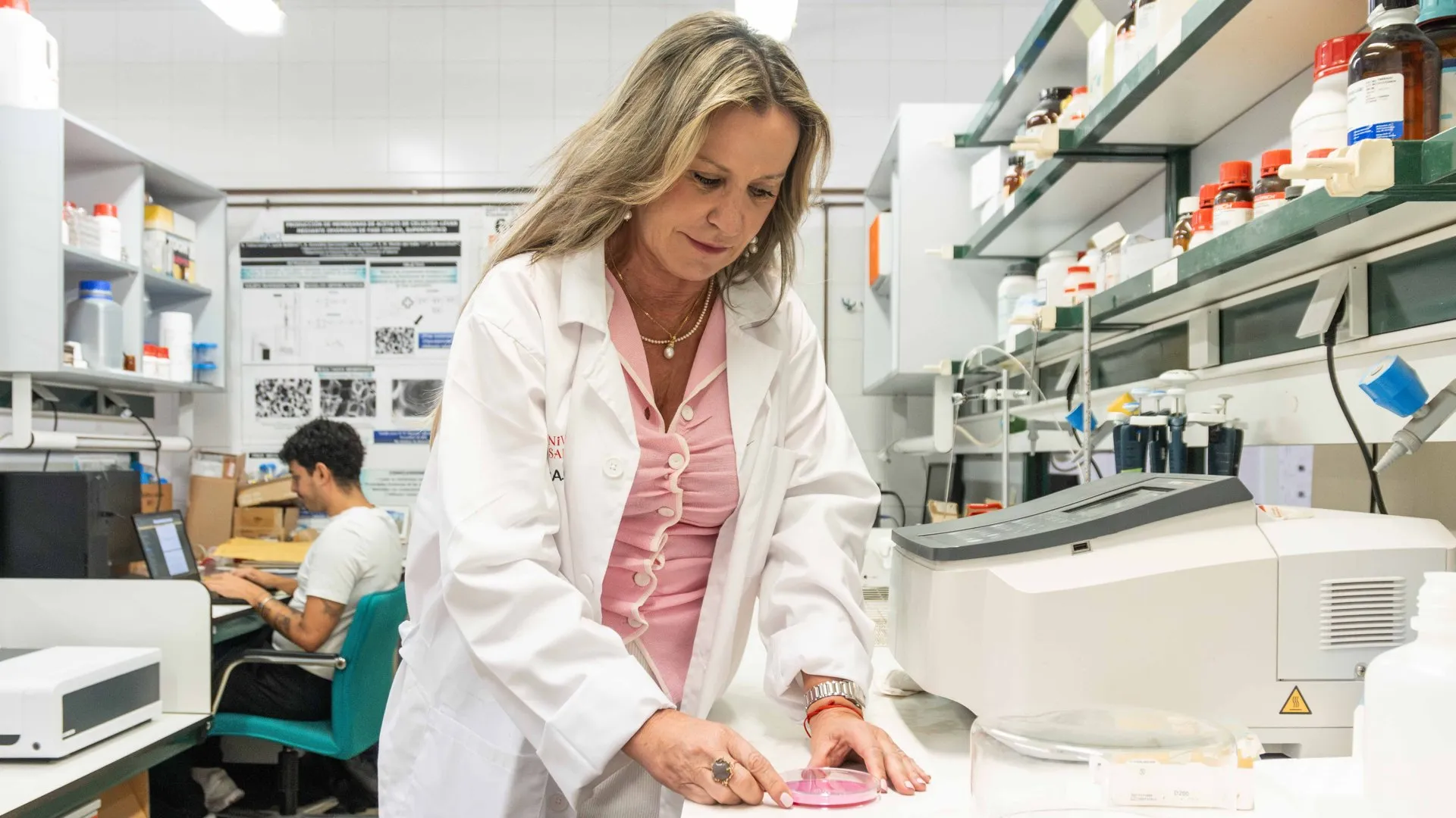 Eva Martín del Valle, con bata blanca, trabaja con una placa de cultivo en su laboratorio de la Universidad de Salamanca